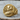 Angled view of 14K gold vermeil Napoleon signet ring resting on wood surface revealing 3D carved military motifs.