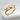 Close-up of elegant stackable diamond wings ring crafted in gold vermeil resting on a white textured stone surface
