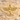 Close-up of the 925 sterling silver based Egyptian Isis pendant in gold resting beautifully on textured beach sand