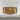 Detailed close up view of Greek mythology ring displayed on textured white stone surface emphasizing sculpted faces