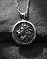 Close-up of silver lion head pendant featuring a detailed profile relief on a textured dark stone background