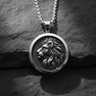 Close-up of silver lion head pendant featuring a detailed profile relief on a textured dark stone background