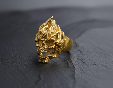 Front view of gold vermeil flaming skull ring featuring intricate fire details on textured black background