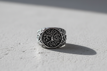 Top view of handcrafted silver Yggdrasil ring with detailed roots and branches on textured background