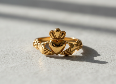 Front view of 14K gold vermeil Claddagh ring featuring hands holding a crowned heart on textured surface