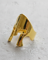 Gold vermeil gladiator helmet ring featuring iconic Spartan design on textured background