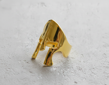 Gold vermeil gladiator helmet ring featuring iconic Spartan design on textured background