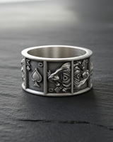 Front view of silver playing card ring on dark slate showing detailed King and Queen of Spades panel engravings