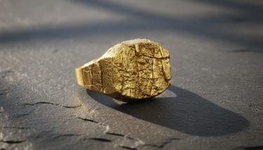 Gold vermeil finish on handcrafted silver grunge rock ring displaying raw cracked stone texture on dark slate background
