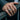 Oxidized silver Hand of God ring worn on a man's hand resting on a metal railing showcasing the textured band