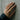 Close-up of textured Aquarius zodiac band ring worn on a woman's hand against a raw concrete wall background
