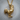 Close-up of handcrafted rooster pendant showing intricate metalwork resting on a natural wood slice background