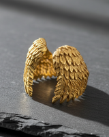14K gold vermeil angel wing ring with textured feathers displayed on dark slate background