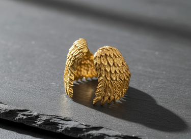 14K gold vermeil angel wing ring with textured feathers displayed on dark slate background