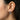 Model wearing silver snake huggie earring displaying wrapping design on ear